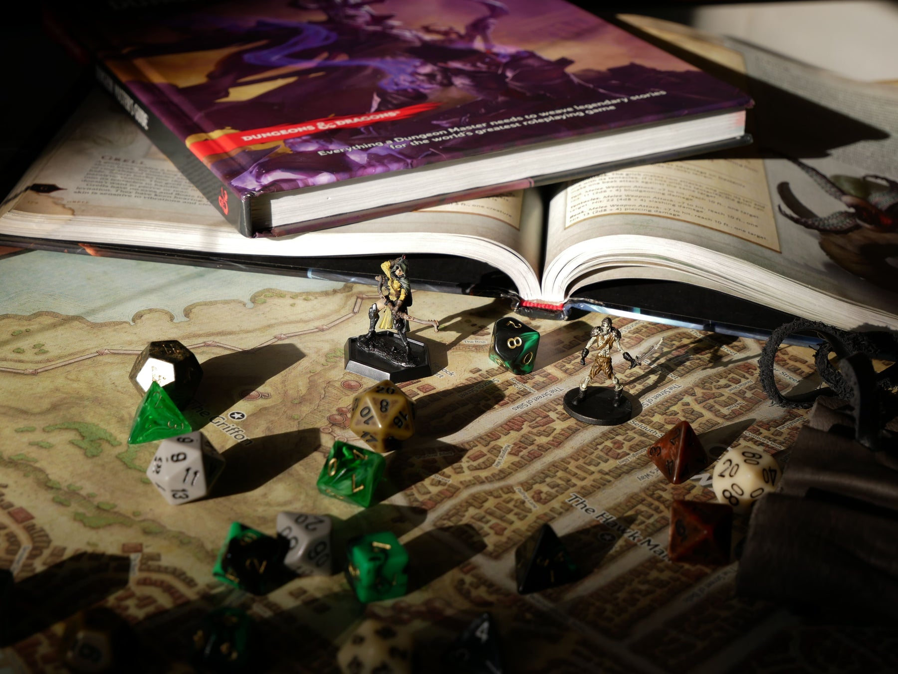 Fantasy miniature figures and polyhedral dice arranged on a tabletop RPG game map